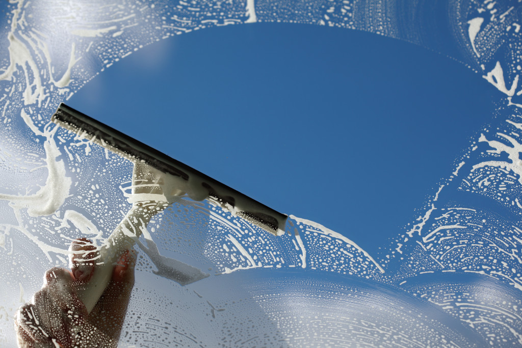 person using squeegee to clean a window